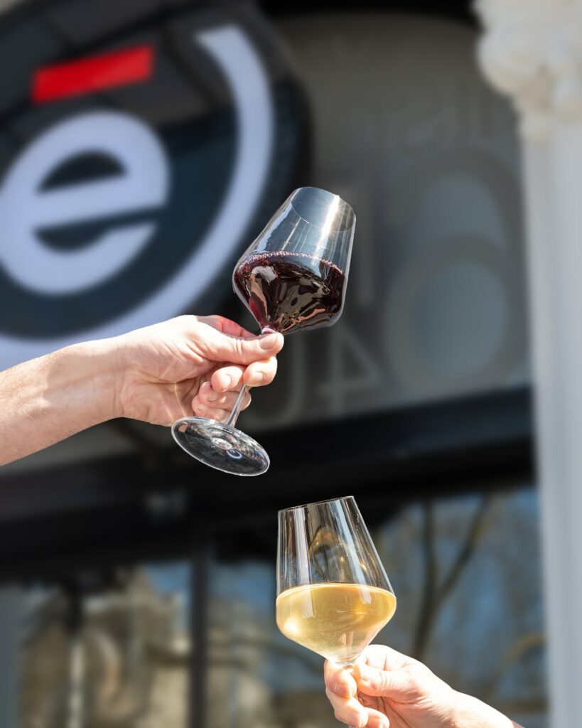 Deux verres de vin, rouge et blanc, que l’on trinque devant l’enseigne de L’Édito
